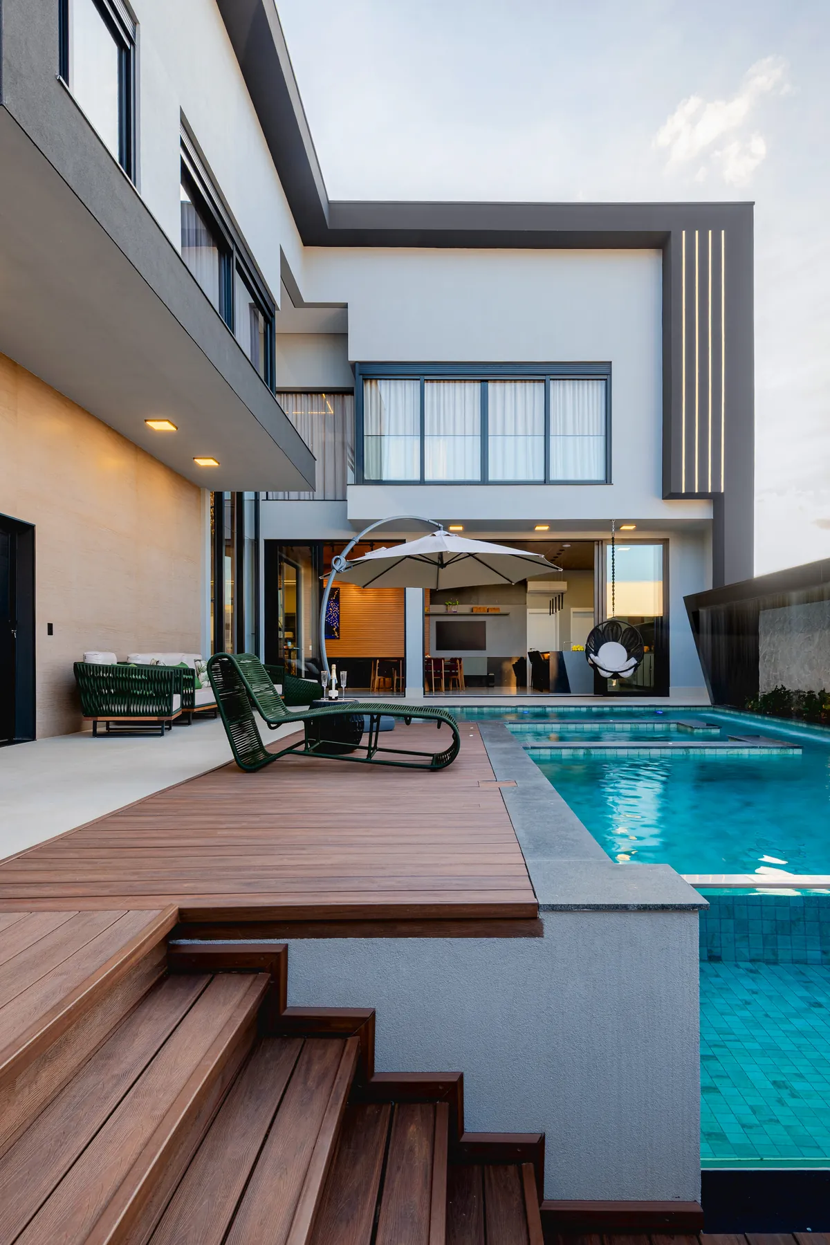 Área de lazer com piscina e deck de madeira em residência de alto padrão